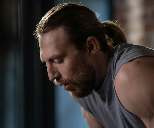Close-up of a determined man's face during a workout, showing focus and concentration.